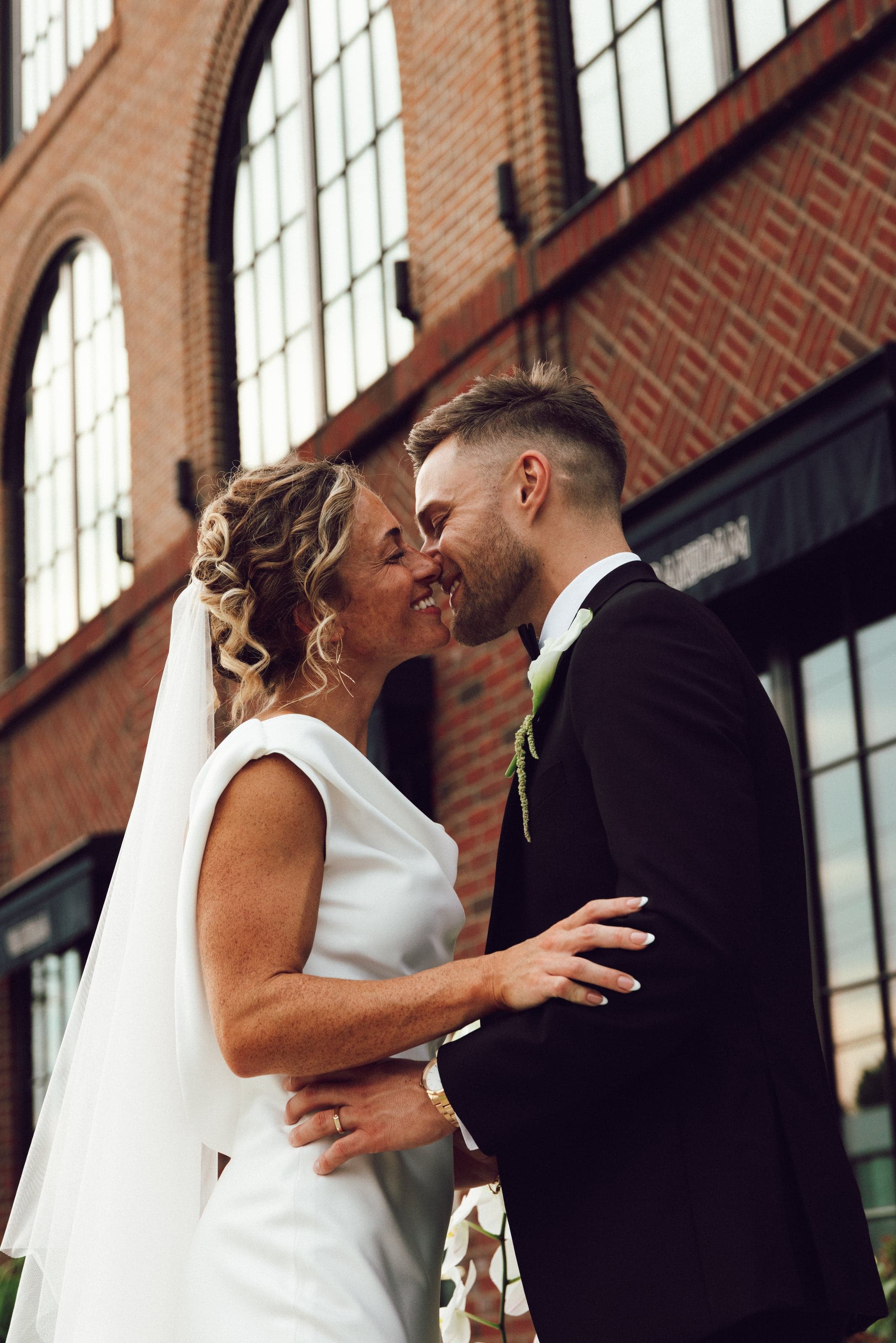 Couple kissing in front of arched brick windows