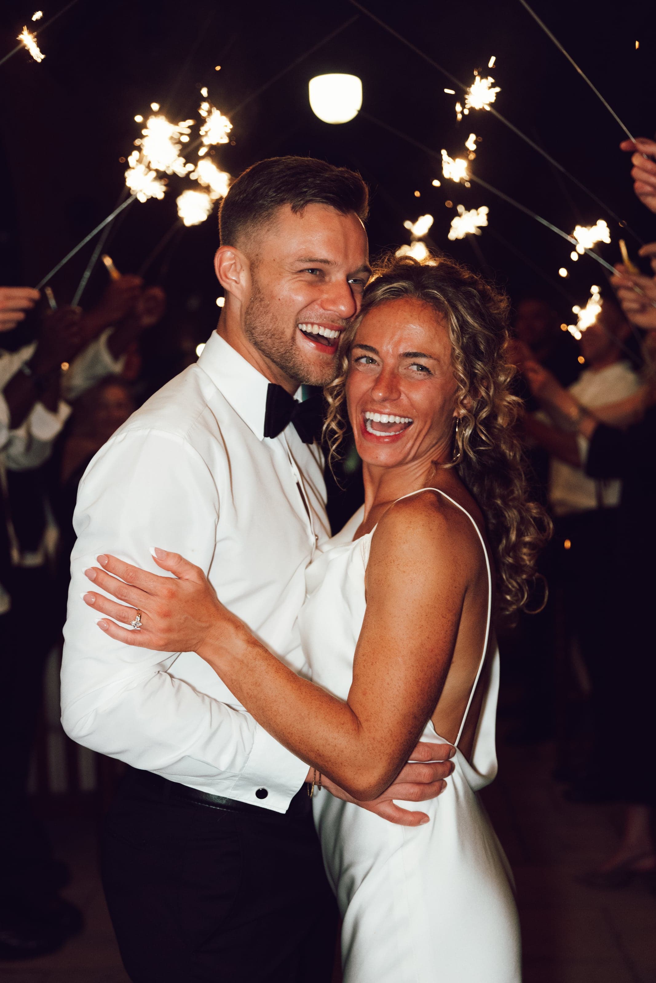 Couple laughing under sparklers at the send-off