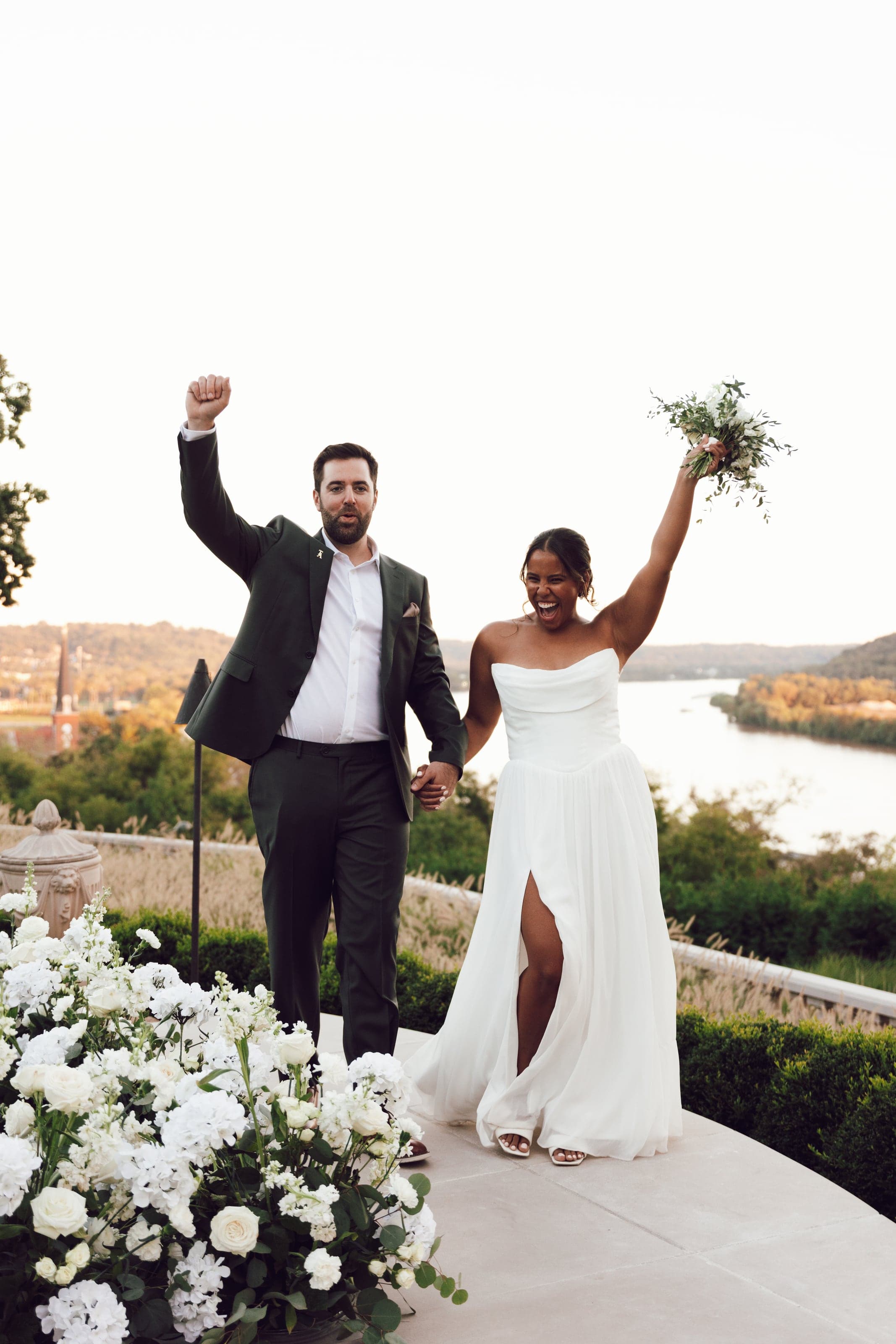 Couple celebrating, arms raised, above a river