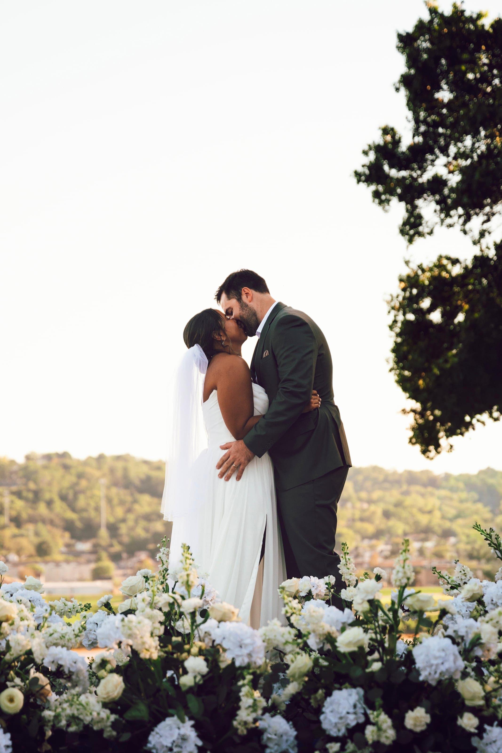 Couple kissing behind a wall of white hydrangeas