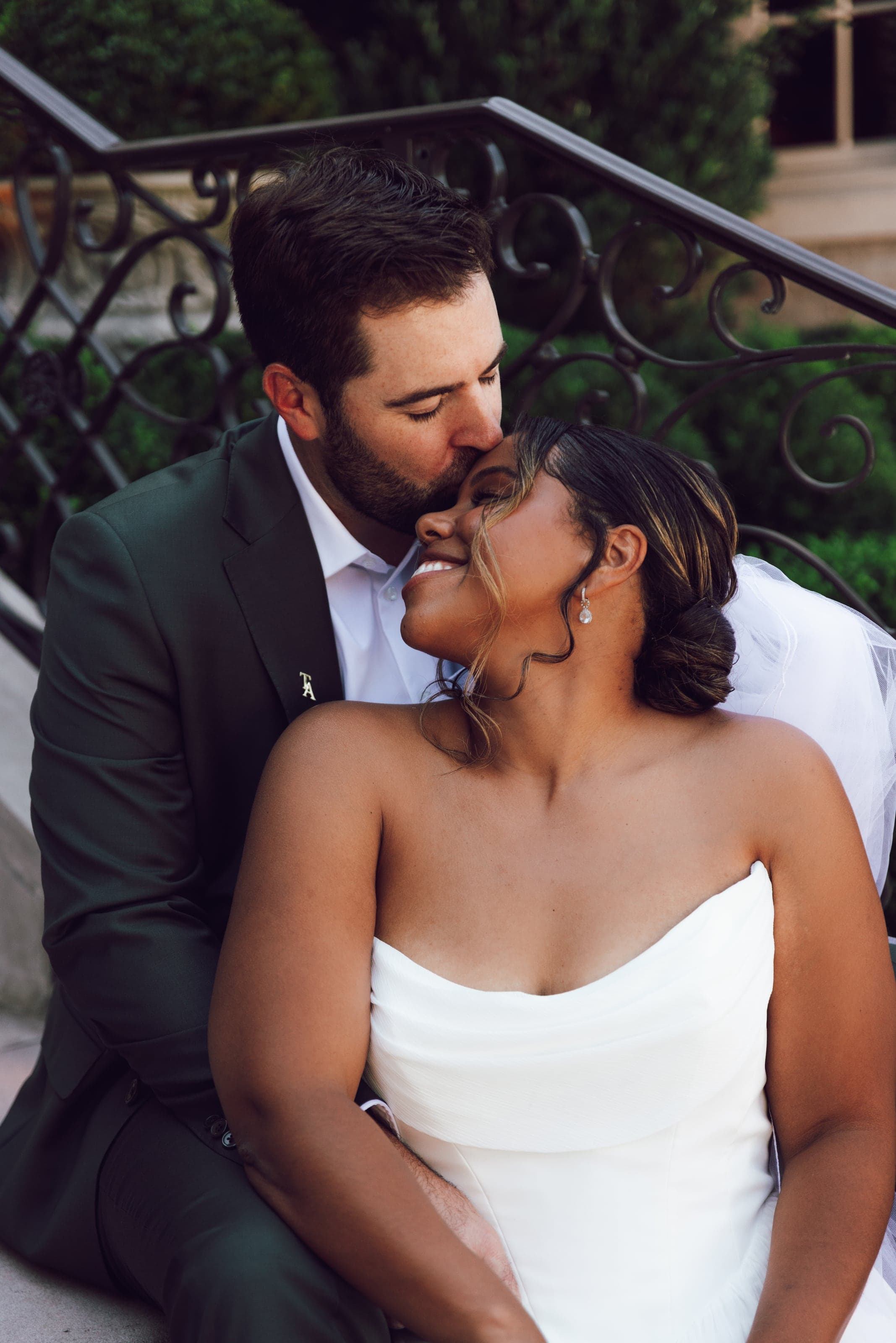 Groom kissing the bride’s forehead as she laughs