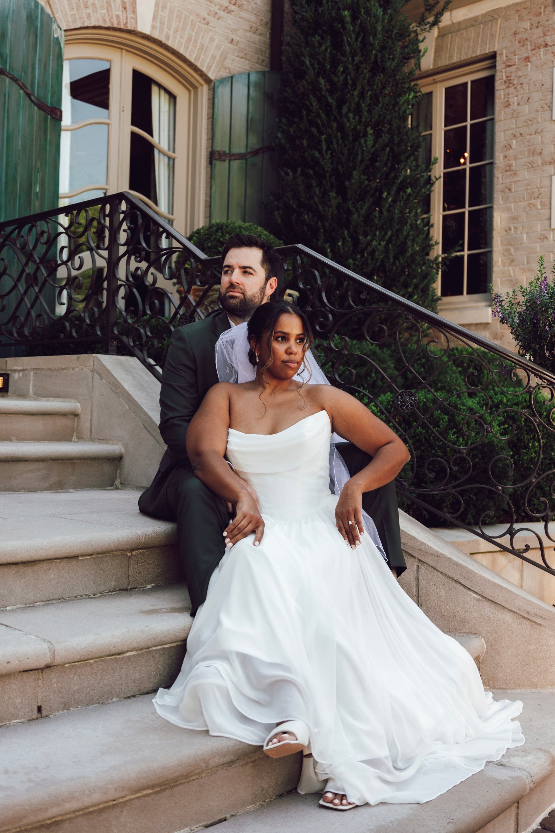 Couple seated on stone stairs with a wrought iron rail